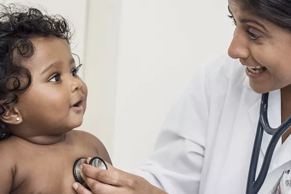Médica examina batimento cardiáco de uma criança